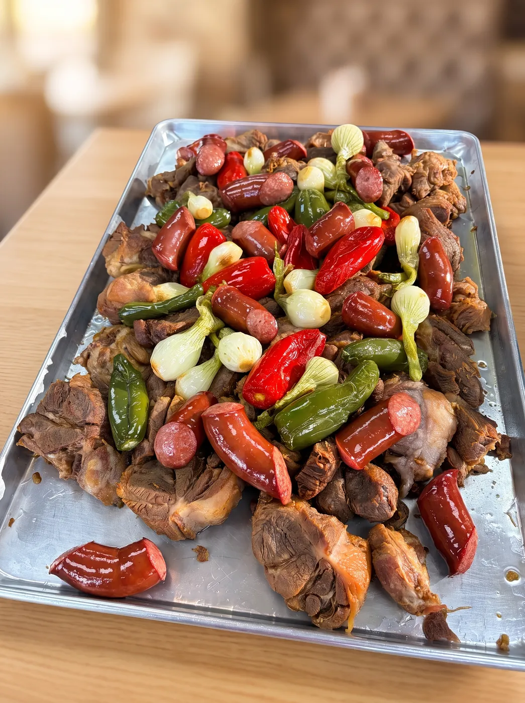 Party tray piled with slow-cooked pork, sausages, grilled spring onions, jalapeños and red peppers